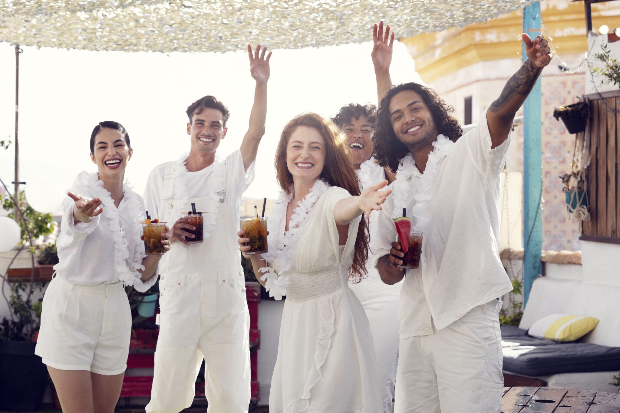 Jóvenes profesionales disfrutando de un evento corporativo en la playa, vestidos de blanco