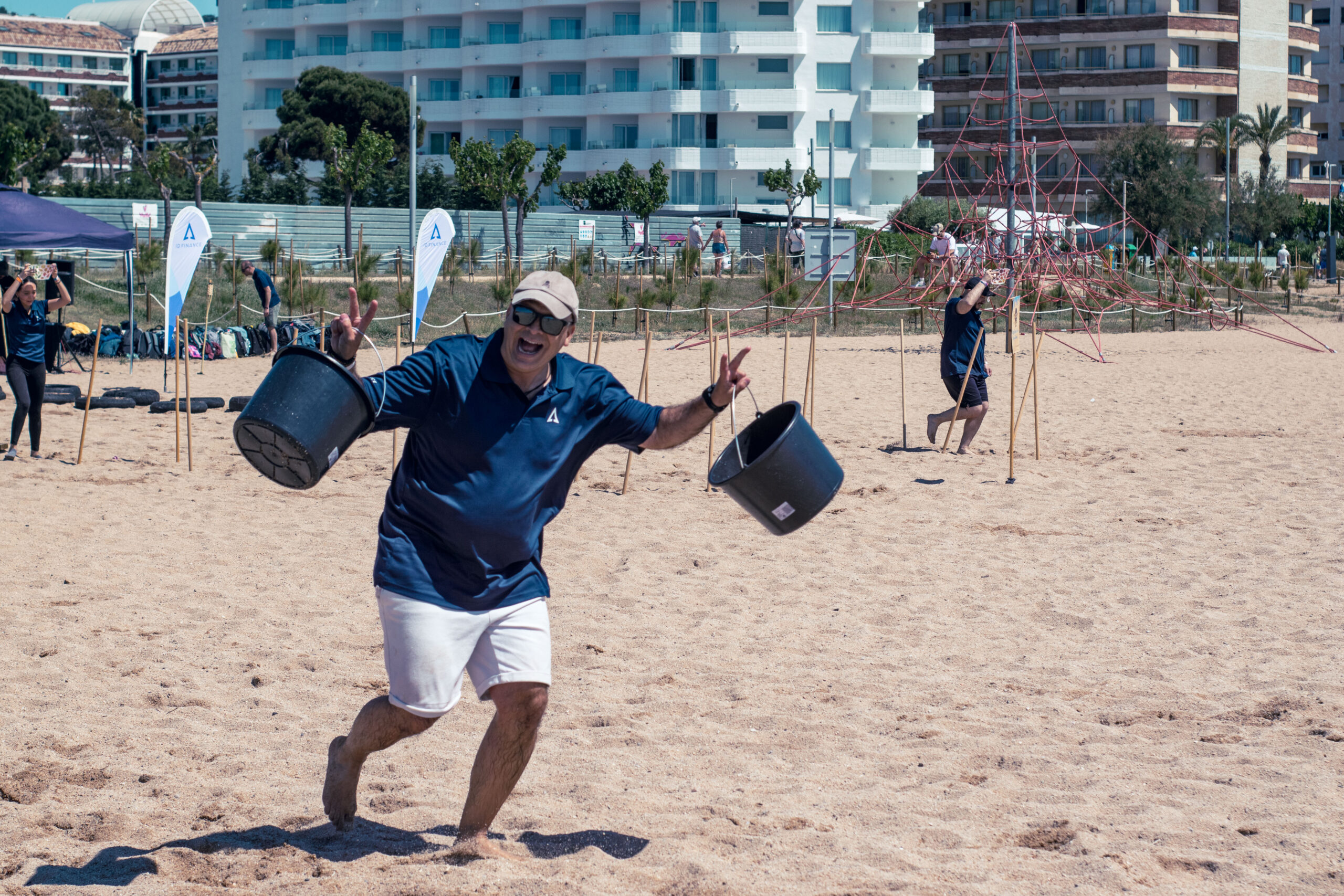 Participante corriendo con cubos de agua hacia el mar durante la carrera de obstáculos