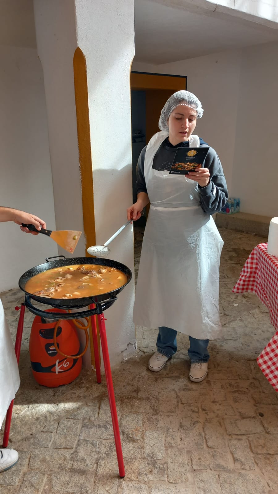 Participante con gorro y delantal revisando la receta oficial en el team building paella valencia