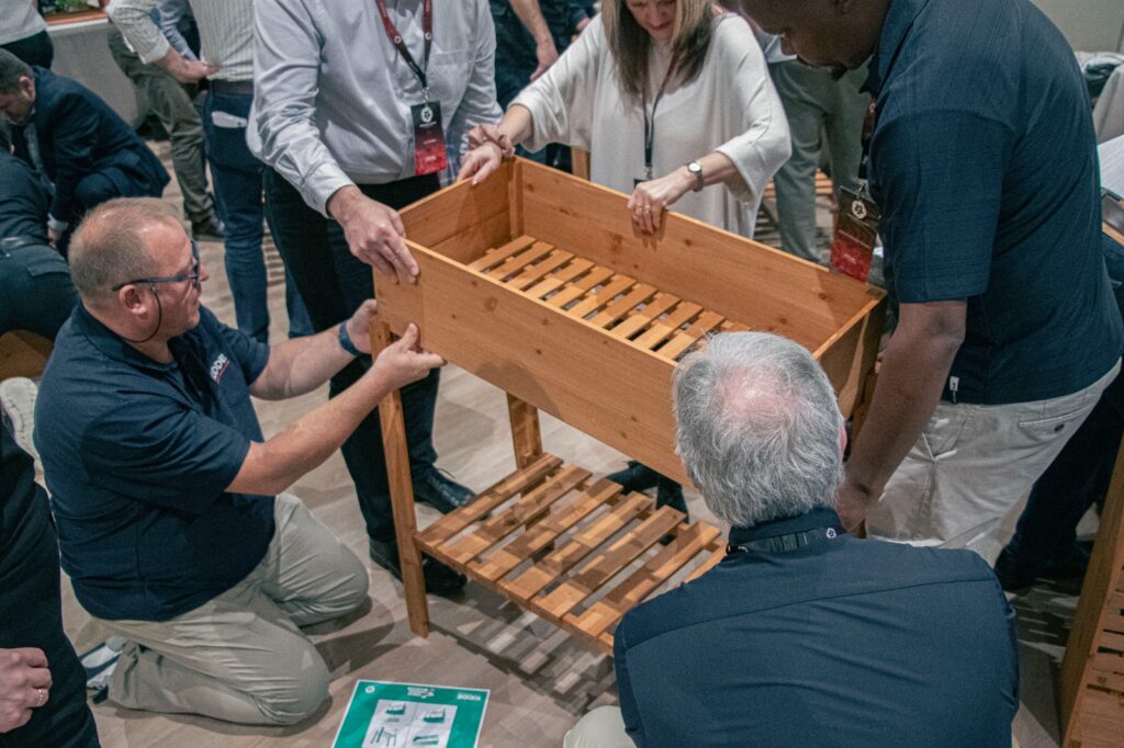equipo de empleados construyendo una jardinera en una actividad solidaria de team building de teamtify