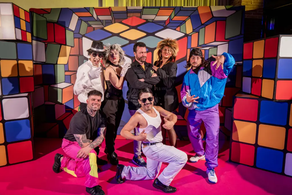 grupo de actores interpretando a personajes como fredy mercury, michael jackson, o tina turner