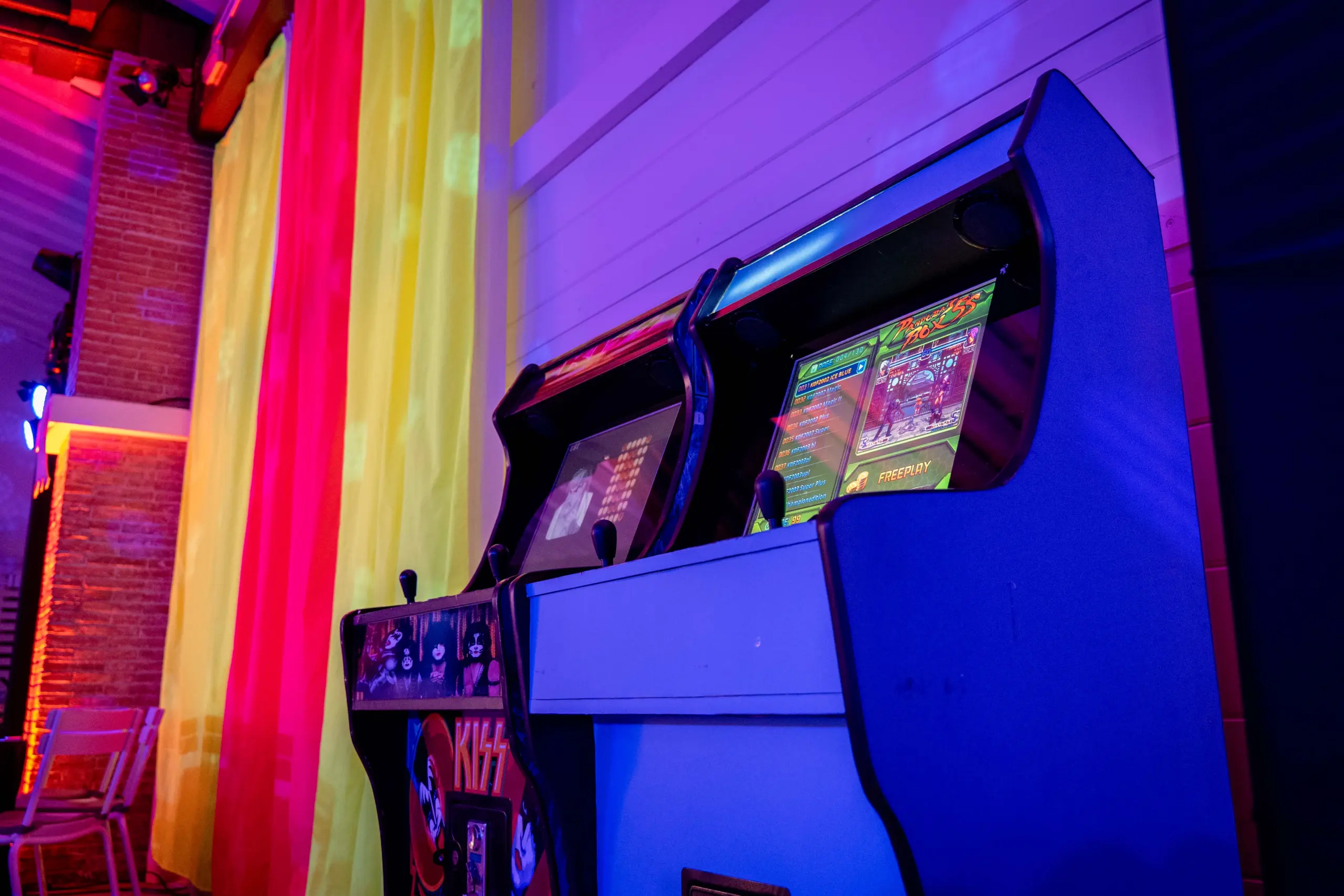 Zona arcade con máquinas Space Invaders y Talent Arena junto a neón Pac-Man en fiesta corporativa años 80