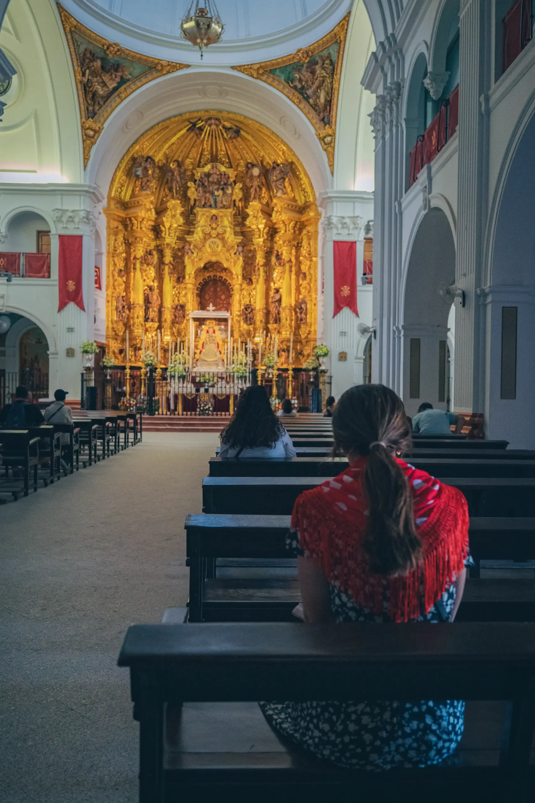 Participante reflexionando de espaldas dentro de la Ermita, observando el espectacular altar barroco de la Virgen del Rocío