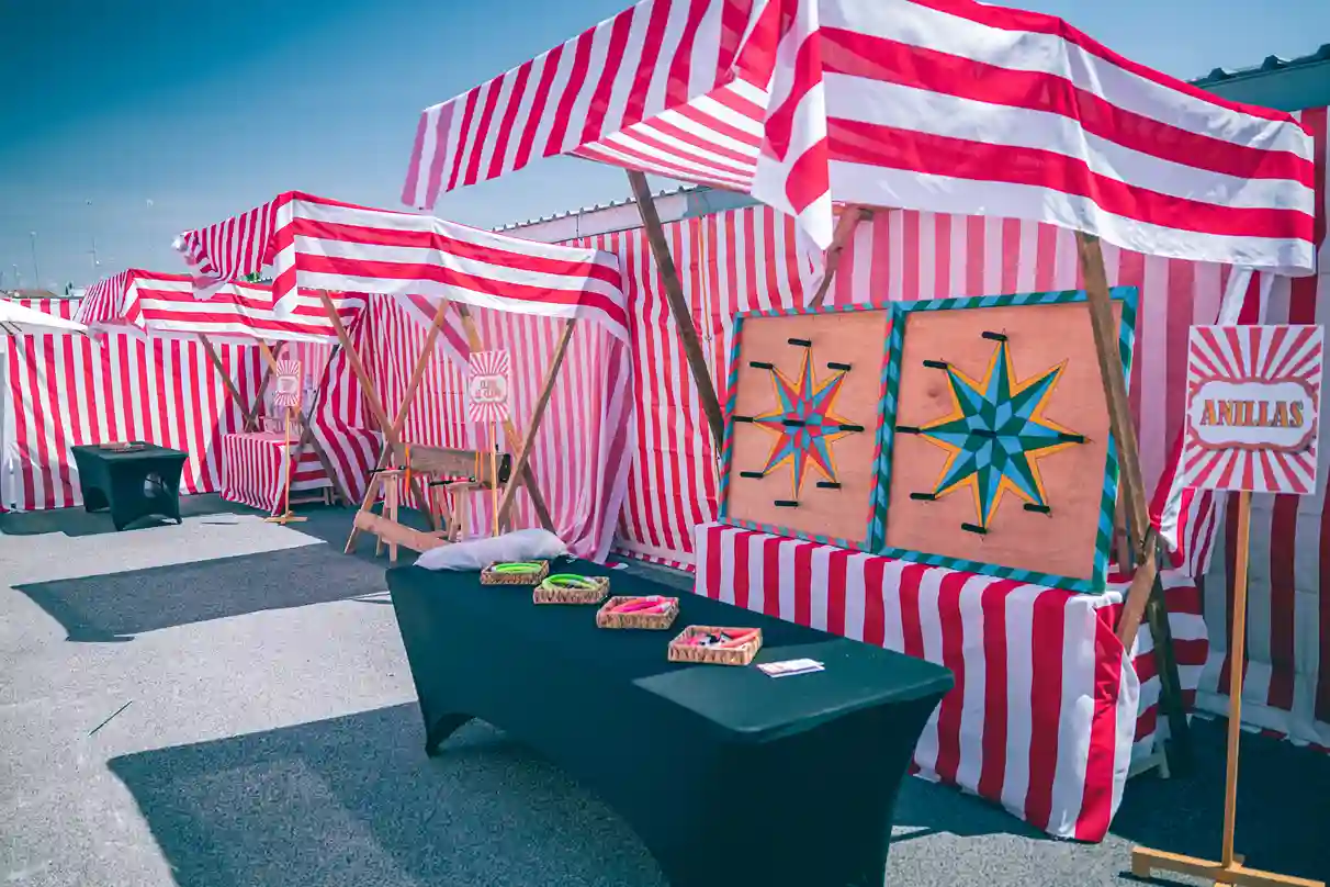 Puestos tradicionales de feria para dinámicas corporativas, incluyendo tiro de anillas y tumba la lata