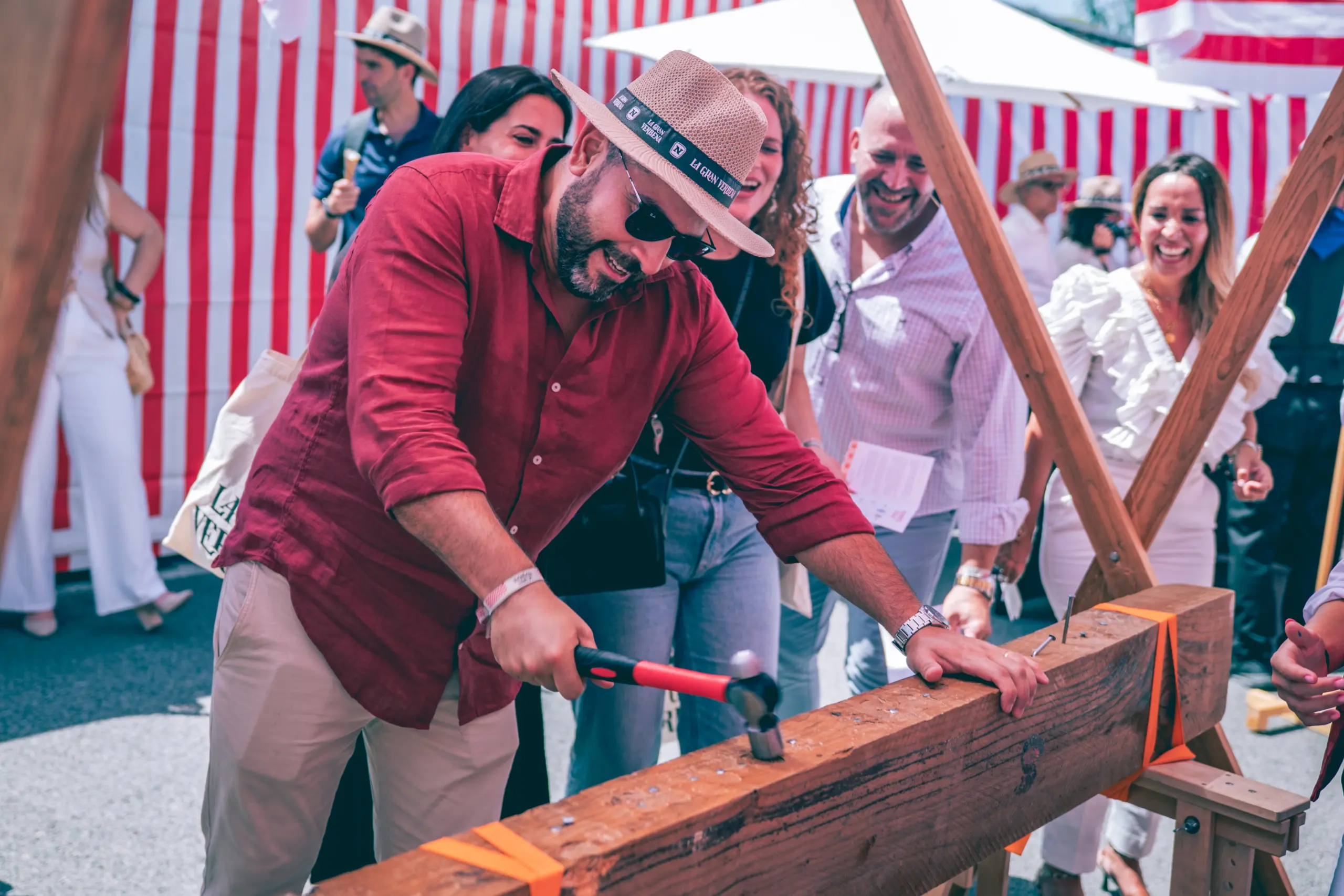 Participante de un evento corporativo concentrado jugando a clavar el clavo en un tronco de madera